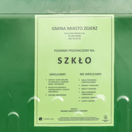 Tabliczka informacyjna umieszczona na zielonym pojemniku