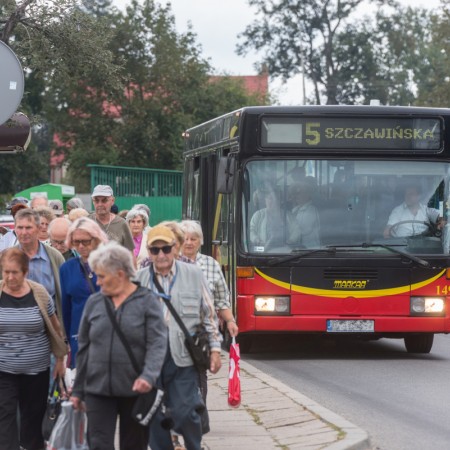 Mieszkańcy wysiadający z autobusu miejskiego na przystanku przy targowisku