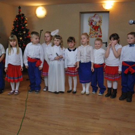 Grupa śpiewających małych dzieci na tle udekorowanej choinki