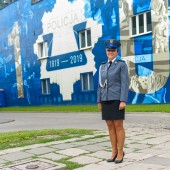 Policjantka w mundurze, w tle mural z okazji 100-lecia policji