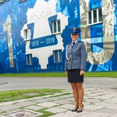 Policjantka w mundurze, w tle mural z okazji 100-lecia policji